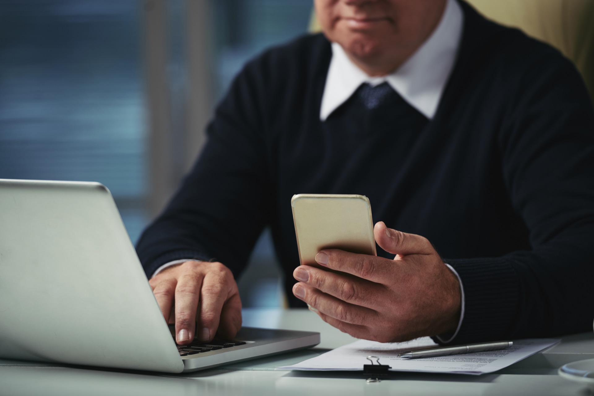 Profissional utilizando laptop e dispositivo móvel para consultoria e planejamento sucessório na Protekto